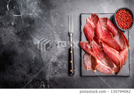 Sliced prsut prshut, Balkan cured pork meat ham. black background. top view Sliced prsut prshut, Balkan cured pork meat ham. black background. top view 130794062