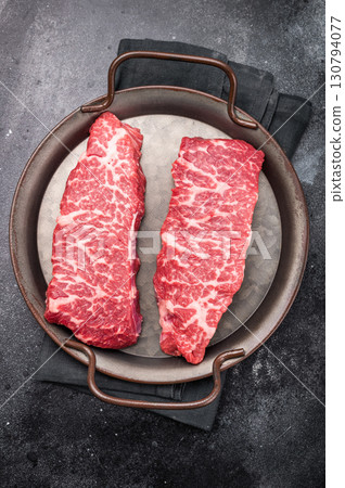 Premium denver, chuck eye steak, beautifully presented, ready for seasoning. A versatile cut ideal for barbecue enthusiasts and steak lovers alike. black background. top view 130794077