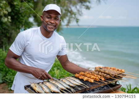 African chef grilling fish and meat skewers at the beach 130794155