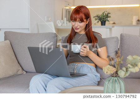 Young woman with coffee cup checks email on laptop works freelance remote tasks client inbox replies 130794792
