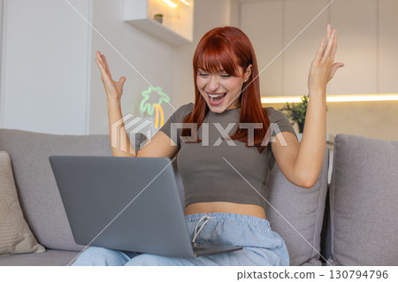 Young woman with laptop finds discount and promo code works jumps celebrates order approval success Young woman with laptop finds discount and promo code works jumps celebrates order approval success 130794796