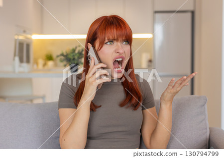 Young woman scolds on smartphone stern brows quick hands asks what why fast talk strong emotion heat 130794799