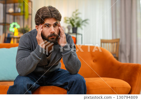 Indian man with head in hands bends forward shows strong emotional fatigue stress burnout tired mood 130794809