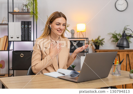 Businesswoman on video lecture earphones nods answers chat runs interview on laptop thanks listeners Businesswoman on video lecture earphones nods answers chat runs interview on laptop thanks listeners 130794813