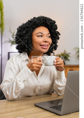 African American businesswoman drinks coffee thinking near window resting from work for inspiration 130794822