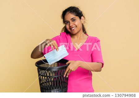Indian woman coughing into elbow, throwing medical mask away, promoting good hygiene and health Indian woman coughing into elbow, throwing medical mask away, promoting good hygiene and health 130794908