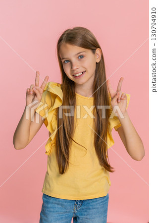 Child girl kid happily showing peace sign gesture with fingers while smiling brightly at camera Child girl kid happily showing peace sign gesture with fingers while smiling brightly at camera 130794910