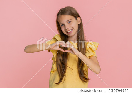 Child girl kid making heart gesture with fingers while smiling to express love friendship emotion 130794911