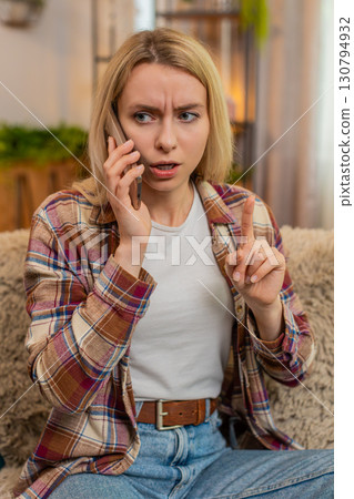 Woman rejecting call on smartphone at home, showing hand gesture to say no with irritated expression Woman rejecting call on smartphone at home, showing hand gesture to say no with irritated expression 130794932