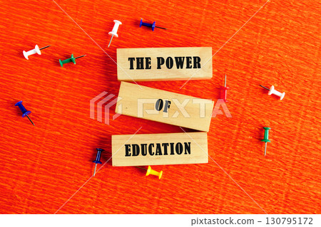 Business and Words Matter concept. Copy space. THE POWER OF EDUCATION assembled from wooden blocks in a composition with stationery pins on an orange provocative background, top view 130795172