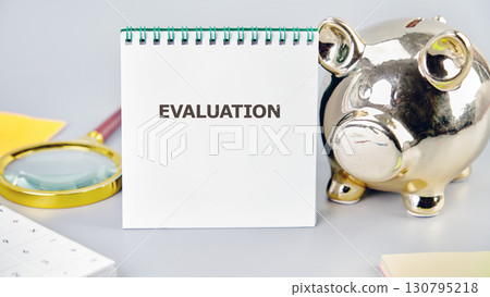 EVALUATION word written in a notebook in a composition with a piggy bank and a magnifying glass. Business risk management concept 130795218