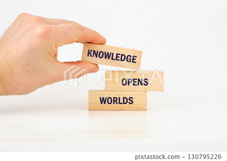 Academic education learning concept. Words KNOWLEDGE OPENS WORLDS made from blocks with hand on white background Academic education learning concept. Words KNOWLEDGE OPENS WORLDS made from blocks with hand on white background 130795226