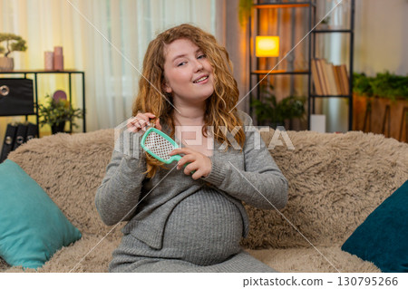 Pregnant young woman brushing hair on home sofa relaxed and calm enjoying peaceful and quiet moment Pregnant young woman brushing hair on home sofa relaxed and calm enjoying peaceful and quiet moment 130795266