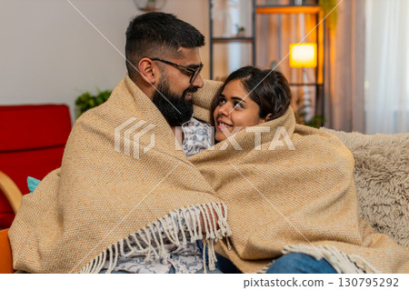Indian family couple man woman cuddling under blanket at home, enjoying silence cozy peaceful moment 130795292