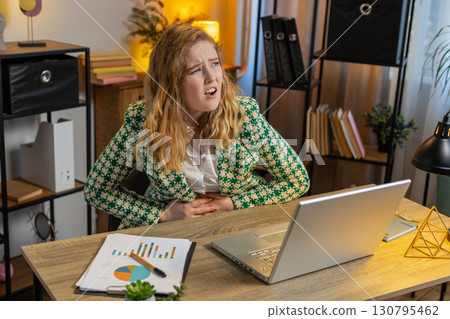 Businesswoman overeating during work process suffering from painful stomach ache menstrual pain Businesswoman overeating during work process suffering from painful stomach ache menstrual pain 130795462