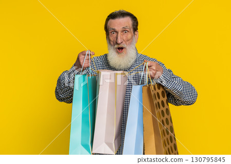 Happy senior old man shows shopping bags advertising discounts amazed with low prices holidays sale Happy senior old man shows shopping bags advertising discounts amazed with low prices holidays sale 130795845