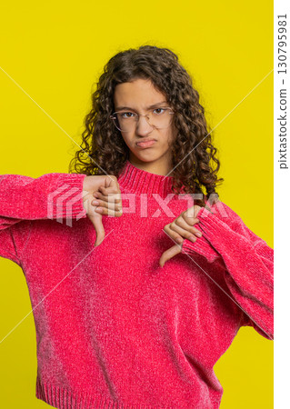Upset girl teen child showing thumbs down gesture disapproval dissatisfied dislike negative feedback 130795981