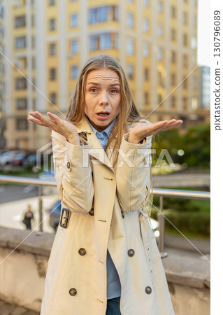 Doubtful sad frustrated mature Caucasian woman shrugging shoulders dont know answer on city street 130796089