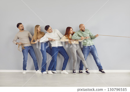 Group of happy strong young friends competing in tug of war and having fun together 130796585