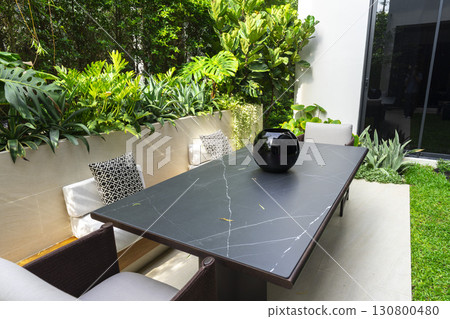 Modern terrace with dining table and chairs. Summer garden space for party. 130800480