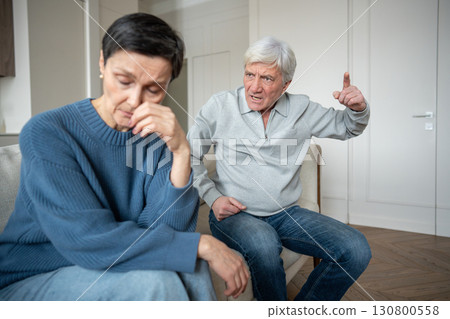 Irritated senior man shouting and gesturing at distressed sad wife, emotional instability and abuse 130800558