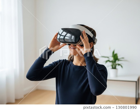 Bright clean room with person wearing VR headset showing curiosity posture reflecting futuristic immersive excitement in simple modern technological lifestyle concept 130801990