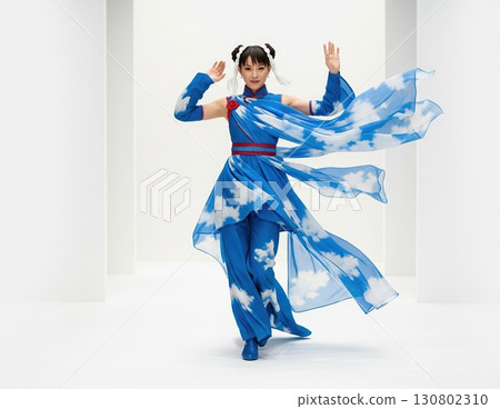 White-background photo of Asian runway contestant wearing a costume shaped like swirling wind, flowing fabrics, and gentle translucent motion 130802310