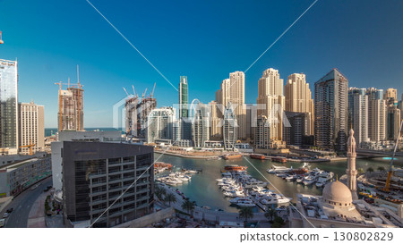 Yachts in Dubai Marina flanked by the Al Rahim Mosque and residential towers and skyscrapers aerial timelapse. 130802829