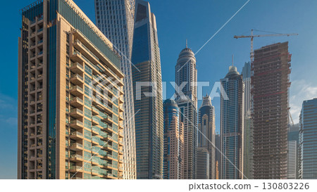 View of modern skyscrapers shining in sunrise lights timelapse in Dubai Marina in Dubai, UAE. View of modern skyscrapers shining in sunrise lights timelapse in Dubai Marina in Dubai, UAE. 130803226
