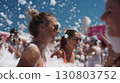 Smiling friends enjoying a lively foam party under the bright summer sun 130803752