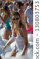 Smiling friends enjoying a lively foam party under the bright summer sun 130803753
