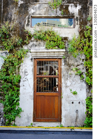 Vintage wooden and wrought iron door with greenery creeper and climber ivy on rustic grunge concrete wall exterior of old house Vintage wooden and wrought iron door with greenery creeper and climber ivy on rustic grunge concrete wall exterior of old house 130804673