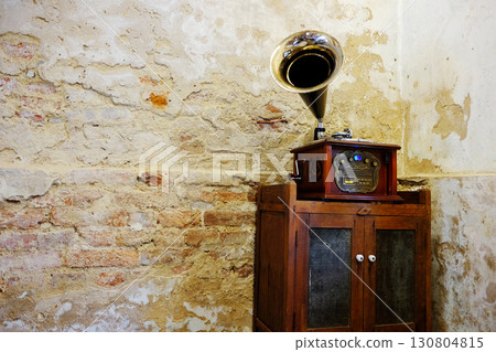 Vintage wooden Gramophone music box on antique wooden cabinet inside grunge concrete and brick wall in Bangkok of Thailand. Copy space 130804815