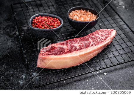 Raw beef picanha steak, featuring a thick layer of fat that adds flavor during cooking. black background. top view 130805009