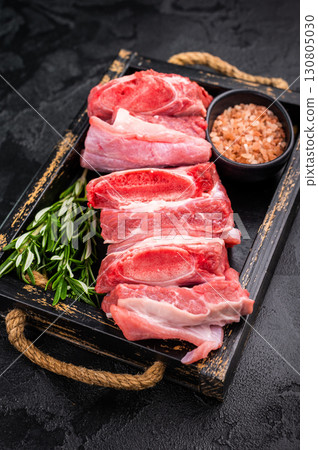 Raw Veal Short Rib, fresh beef meat with bone and herbs for cooking . black background. top view 130805030