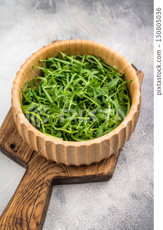 Fresh arugula leaves, vibrant and peppery, perfect for adding a zesty touch to salads and sandwiches. grey background. top view Fresh arugula leaves, vibrant and peppery, perfect for adding a zesty touch to salads and sandwiches. grey background. top view 130805036