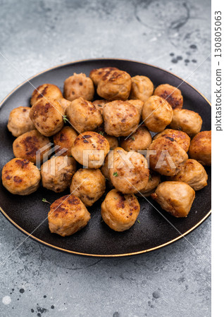 Savory meatballs, meat dumplings garnished with fresh herbs. A delightful addition to any meal, bringing warmth and satisfaction to the table. grey background. top view Savory meatballs, meat dumplings garnished with fresh herbs. A delightful addition to any meal, bringing warmth and satisfaction to the table. grey background. top view 130805063