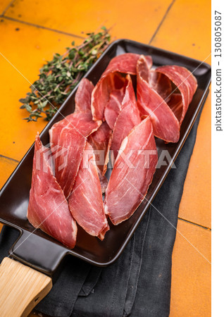Serbian ham Prsut, sliced cured pork meat on plate. orange background. top view Serbian ham Prsut, sliced cured pork meat on plate. orange background. top view 130805087