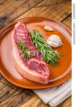 Raw sirloin beef steak, featuring a vibrant hue and well defined grain. wooden background. top view 130805090