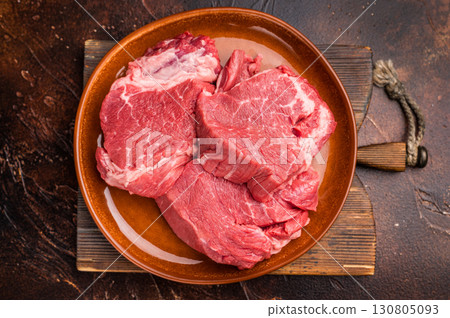 Raw Beef meat medallions on a decorative plate, fresh steaks ready for cooking. black background. top view 130805093