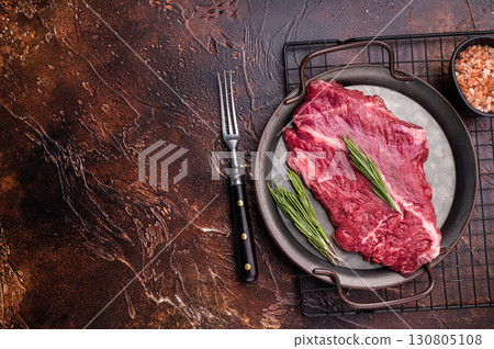 Raw hanger tender beef steak, skirt steak with rosemary on steel tray. brown background. top view 130805108