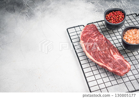 Fresh raw top sirloin steak, showcasing its rich color and marbling. grey background. top view Fresh raw top sirloin steak, showcasing its rich color and marbling. grey background. top view 130805177