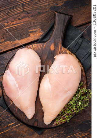Boneless chicken breasts, neatly arranged on a cutting board. The perfect choice for meal prep or a delicious family dinner. wooden background. top view Boneless chicken breasts, neatly arranged on a cutting board. The perfect choice for meal prep or a delicious family dinner. wooden background. top view 130805201