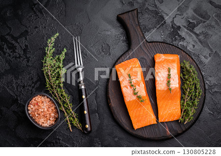Fresh Salmon fillet steak, raw fish meat on a wooden board with herbs. black background. top view 130805228