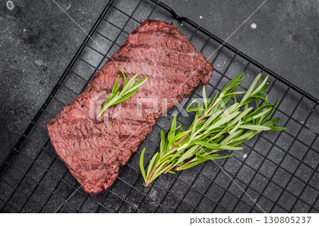 Grilled Flank steak, beef meat on rack with rosemary. black background. top view Grilled Flank steak, beef meat on rack with rosemary. black background. top view 130805237