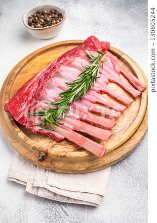 Uncooked rack of lamb, raw mutton chops on wooden board. grey background. top view 130805244