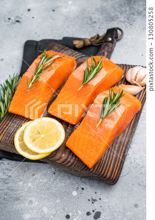 Salmon steaks, raw fish fillets on a wooden board. grey background. top view Salmon steaks, raw fish fillets on a wooden board. grey background. top view 130805258