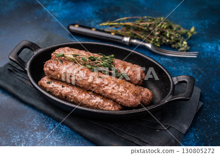 Grilled Cevapcici Sausage, roasted Cevapi from mince beef and pork meat in a skillet. blue background. top view Grilled Cevapcici Sausage, roasted Cevapi from mince beef and pork meat in a skillet. blue background. top view 130805272