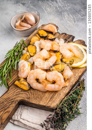 Fresh Seafood cocktail, raw Mix with Mussels, Clams, Prawns, Shrimps and squid on wooden board. white background. top view Fresh Seafood cocktail, raw Mix with Mussels, Clams, Prawns, Shrimps and squid on wooden board. white background. top view 130805285