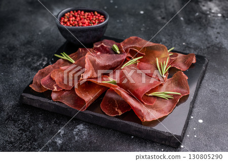 Dried spanish meat slices cecina, spanish tapa. black background. top view Dried spanish meat slices cecina, spanish tapa. black background. top view 130805290